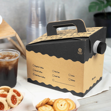 Load image into Gallery viewer, Cardboard beverage to-go container with a handle on a table with flavor selection options